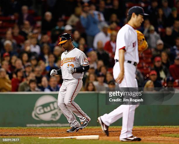 Alexi Casilla of the Baltimore Orioles, pinch running for Danny Valencia, scores the winning run on a sacrifice fly as Koji Uehara of the Boston Red...