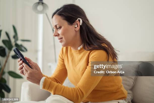 hearing impaired woman using cellphone at home - deafness stock pictures, royalty-free photos & images