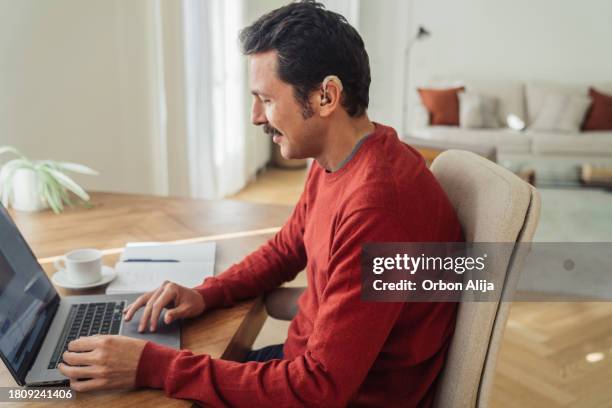hearing impaired man using computer at home - deafness stock pictures, royalty-free photos & images