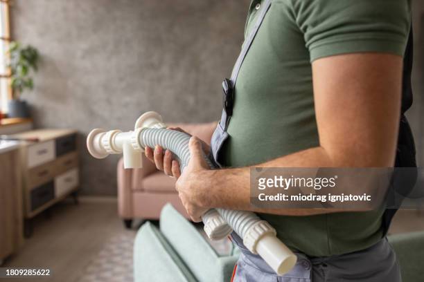 plumber repairing a broken sink in a clients apartment - handyman overalls stock pictures, royalty-free photos & images