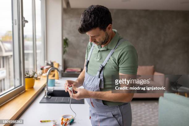 electrician repairing a light bulb socket in an apartment - handyman overalls stock pictures, royalty-free photos & images