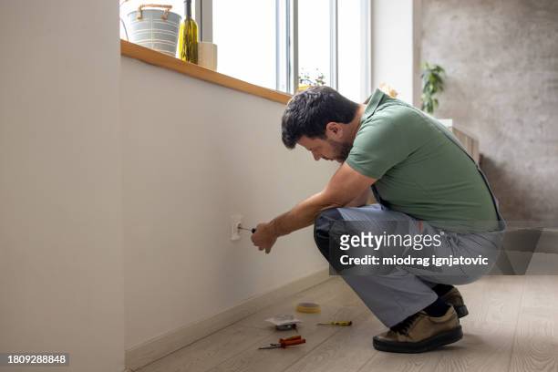 electrician repairing a power outlet in an apartment - handyman overalls stock pictures, royalty-free photos & images