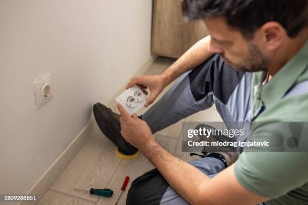 electrician repairing a power outlet in an apartment - handyman overalls stock pictures, royalty-free photos & images