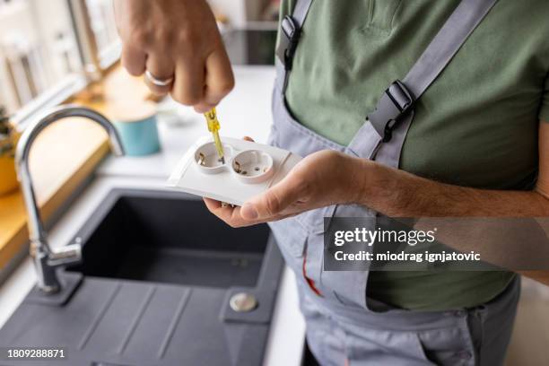 electrician repairing a power outlet in an apartment - handyman overalls stock pictures, royalty-free photos & images