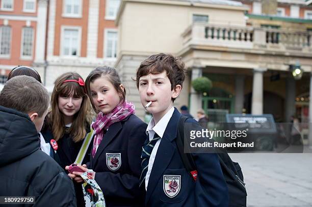 Young schoolboy smokes a cigarette in Covent Garden Piazza, London.