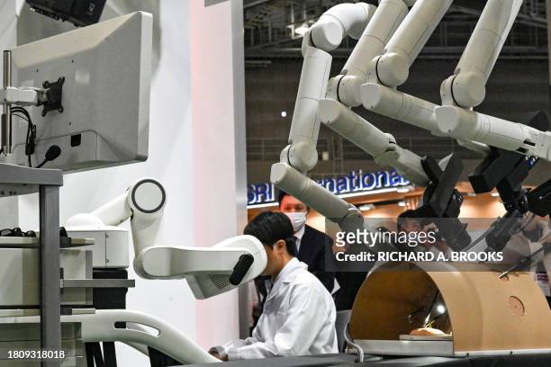Technician uses robots to tie sutures during a surgery demonstration by medical robot company Medicaroid at the Kawasaki booth, on the first day of...