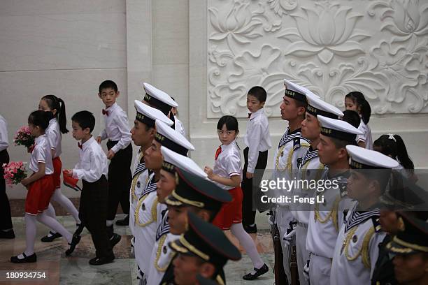 Children look at Chinese navy soldiers of a guard of honor as they prepare for the welcoming ceremony for King Abdullah II Ibn Al Hussein of Jordan...