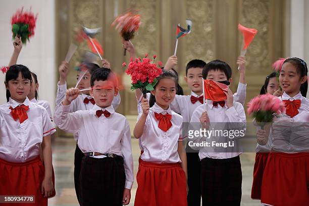 Children wave flags and flowers as they prepare for the welcoming ceremony for King Abdullah II Ibn Al Hussein of Jordan at the Great Hall of People...