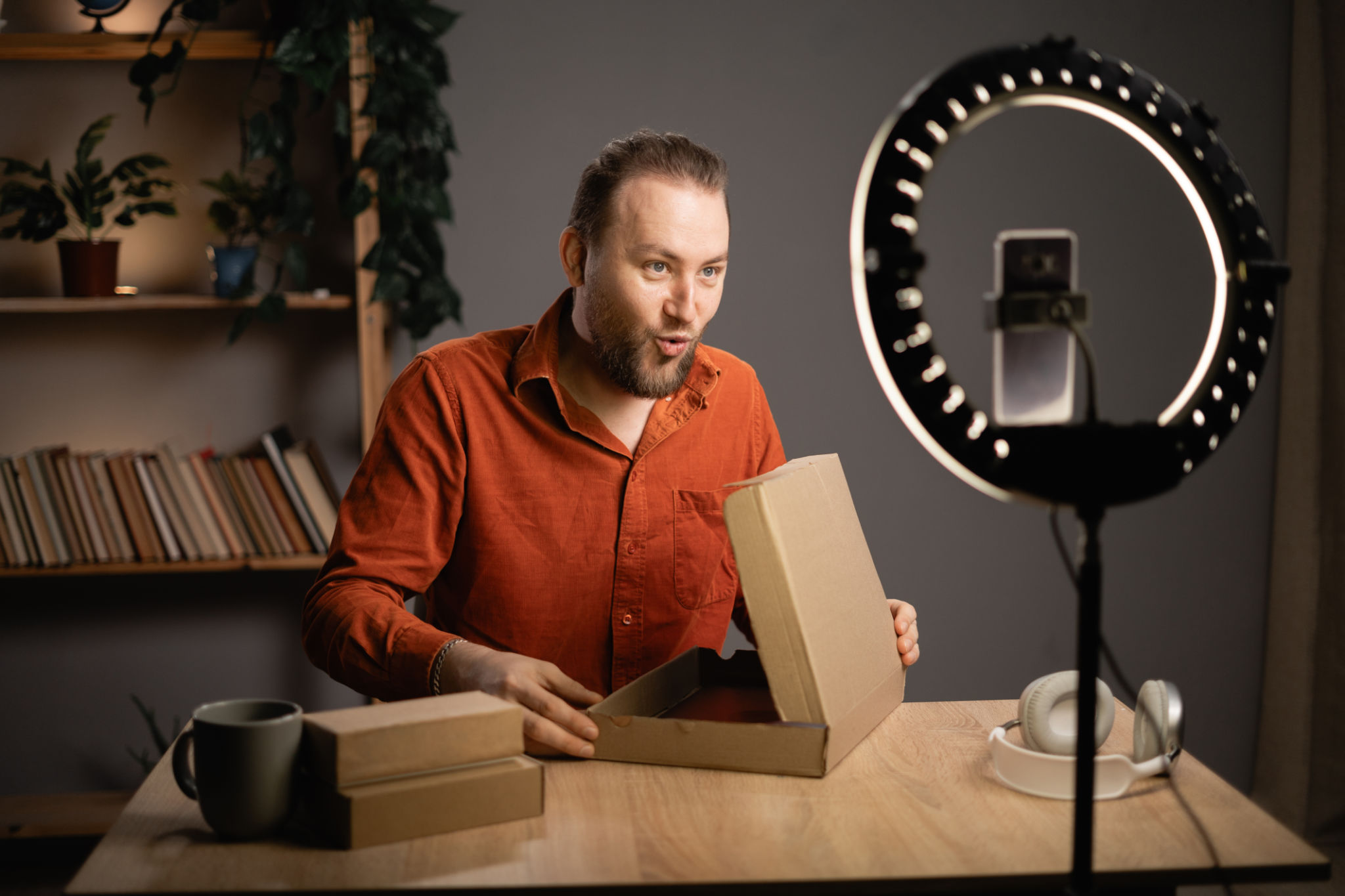Male influencer unboxing a product and shooting video for social media sitting in authentic home interior. Male influencer unboxing a product and shooting video for social media sitting in authentic home interior.