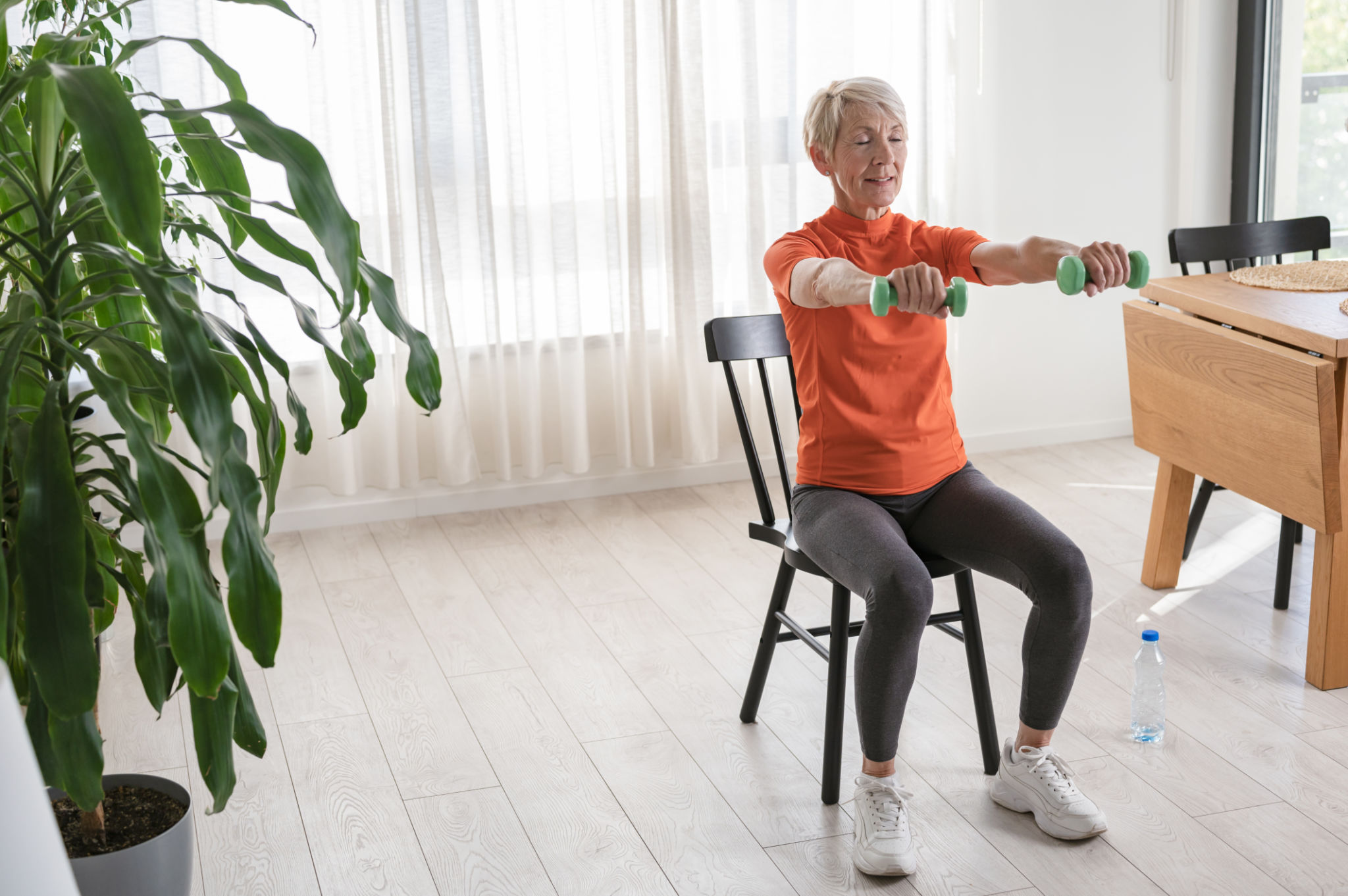 Smiling beautiful senior woman health instructor doing chair exercises Smiling beautiful senior woman health instructor doing chair exercises