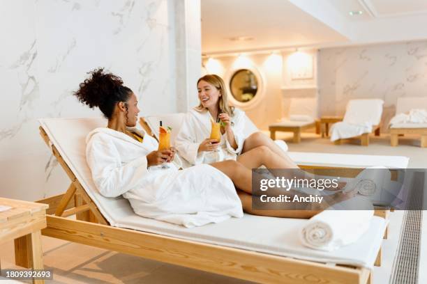 mujeres sonrientes bebiendo cócteles junto a la piscina - hotel de lujo fotografías e imágenes de stock