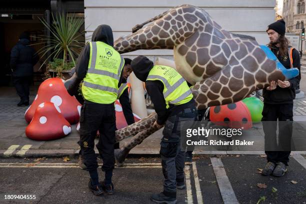 Work crew organises and carries fibreglass props including a headless giraffe into a venue for a forthcoming event promoting the new Willy Wonka film...
