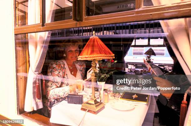 Passengers view a menu at a table in a pullman dining car of the Venice Simplon Orient Express luxury train service prior to departing from Victoria...