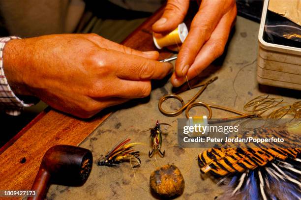 Local fisherman makes his own hand tied artificial fly lures, a type of fishing lure, to be used for fly fishing on the nearby River Tyne near his...