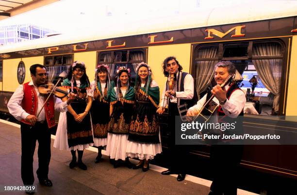 Hungarian folk musicians entertain passengers as they board a pullman car of the Venice Simplon Orient Express luxury train service at Victoria...