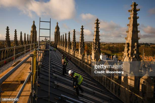 Construction workers prepare the roof for the installation of solar panels at King's College Chapel at Cambridge University in Cambridge, UK, on...