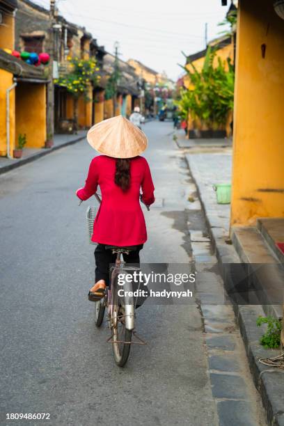 vietnamese woman riding a bicycle, old town in hoi an city, vietnam - traditional clothing stock pictures, royalty-free photos & images