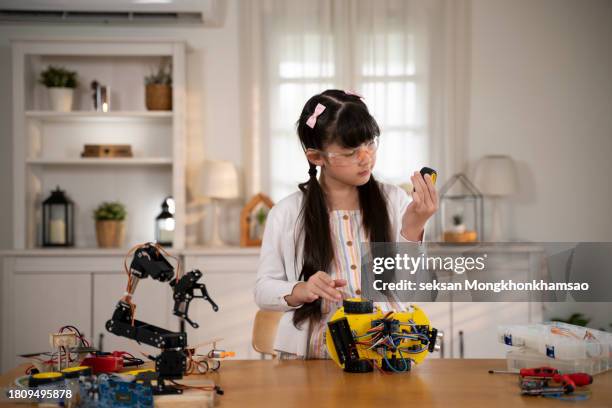 caucasian schoolgirl, adjusting her prototype of an autonomous self-driven robotic car with screwdriver - school science project stock pictures, royalty-free photos & images