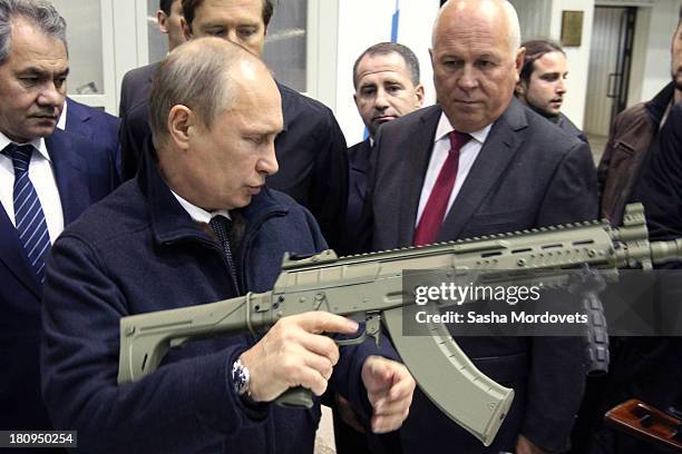 Russian President Vladimir Putin holds a Kalashnikov machine gun during his visit to the Kalashnikov manufacturing plant September 18, 2013 in...