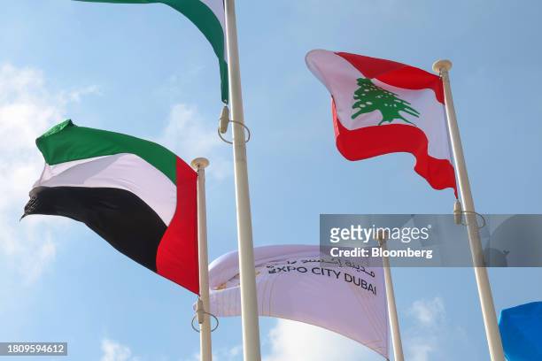 National flags of the United Arab Emirates, left, and Lebanon, right, outside the Green Zone entrance ahead of the COP28 climate conference at Expo...