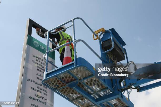 Worker in a cherry picker installs signage in the Green Zone ahead of the COP28 climate conference at Expo City in Dubai, United Arab Emirates, on...