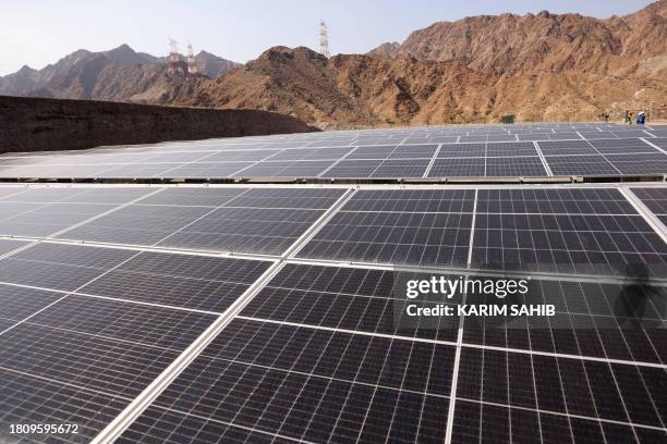 An engineer walks past solar panels at the ADNOC Facility in Fujairah on November 28, 2023. Using novel technology developed by Omani start-up 44.01,...