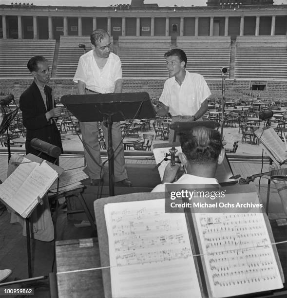 Pop singer Frank Sinatra performs onstage during a soundcheck with Max Steiner conducting the orchestra at Lewisohn Stadium on August 3, 1943 in New...