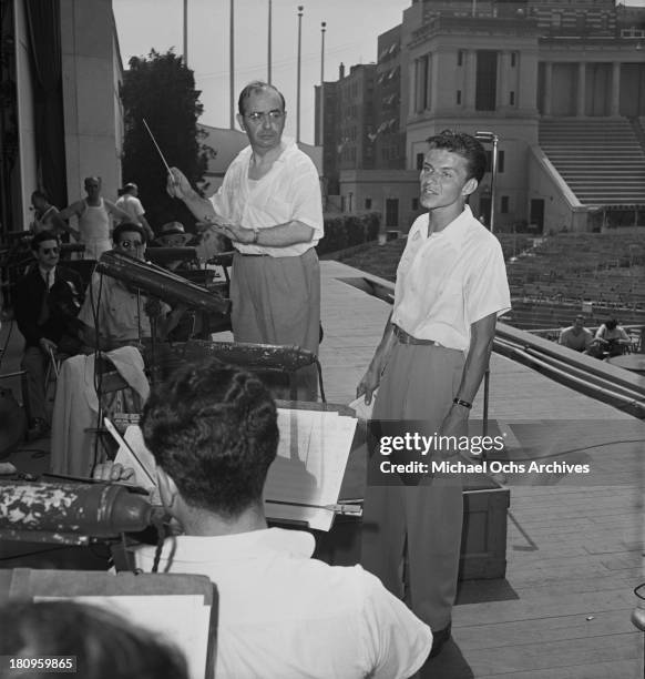 Pop singer Frank Sinatra performs onstage during a soundcheck with Max Steiner conducting the orchestra at Lewisohn Stadium on August 3, 1943 in New...