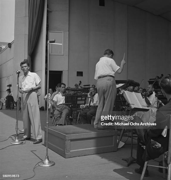 Pop singer Frank Sinatra performs onstage during a soundcheck with Max Steiner conducting the orchestra at Lewisohn Stadium on August 3, 1943 in New...