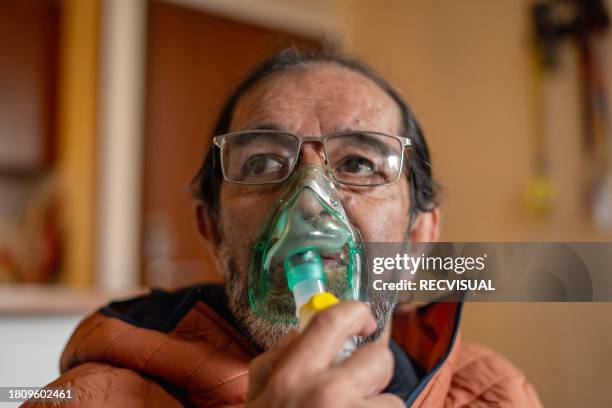 portrait of an older man doing inhalation with oxygen mask. - oxygen mask stock pictures, royalty-free photos & images