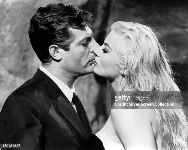 Italian actor Marcello Mastroianni , as Marcello Rubini, and Swedish-American actress Anita Ekberg as Sylvia, kissing, in 'La Dolce Vita', directed...