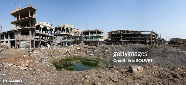 Flaque d'eau et immeubles détruits lors de la bataille de Mossoul le 29 mars 2017.