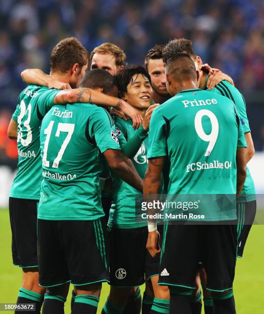 Atsuto Uchida of Schalke celebrates scoring the opening goal with team mates during the UEFA Champions League Group E match between FC Schalke 04 and...