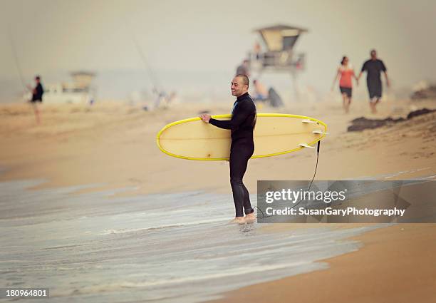 smiling young man with surfboard - huntington beach stock pictures, royalty-free photos & images