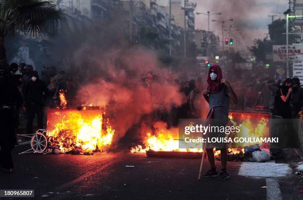 Greek protester stands in front of burning garbage as thousands gather in Keratsini, a western suburb of Athens, after a musician was murdered by a...