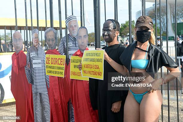 Protesters fancy dressed as the president of Brazil's Supreme Court Joaquim Barbosa and popular singer "Bandida" pose along dummies of accused during...