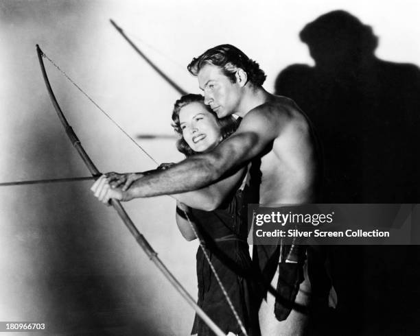 American actors Lex Barker as Tarzan, and Brenda Joyce , as Jane, aiming a bow and arrow in a promotional portrait for 'Tarzan's Magic Fountain',...