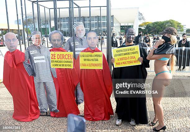 Protesters fancy dressed as the president of Brazil's Supreme Court Joaquim Barbosa and popular singer "Bandida" pose along dummies of accused during...