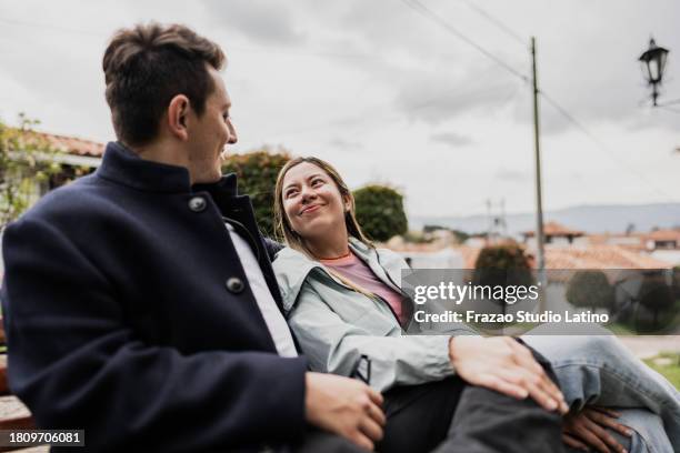 young couple talking on bench outdoors - heteroseksueel koppel stockfoto's en -beelden