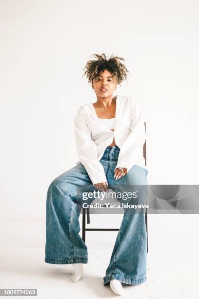 a beautiful young woman posing on the chair in a white studio - actress icon stock pictures, royalty-free photos & images