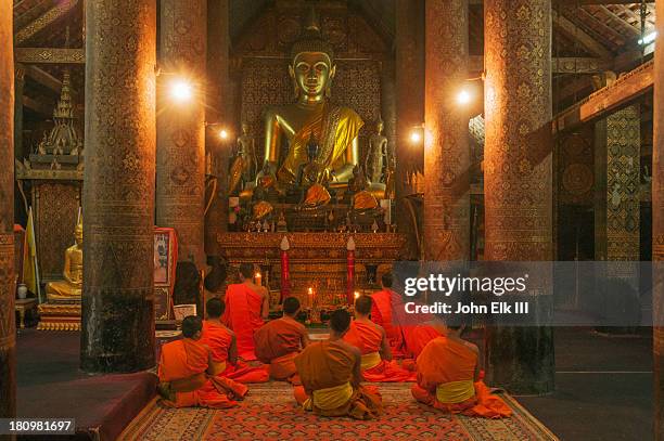 buddha and monks inside wat xieng thong - luang prabang stock pictures, royalty-free photos & images
