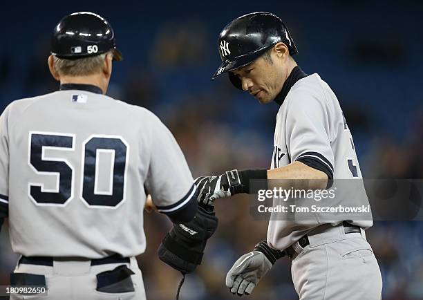 Ichiro Suzuki of the New York Yankees is congratulated by Mick Kelleher after hitting a single in the ninth inning during MLB game action against the...