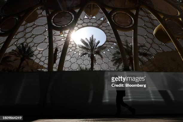 An attendee checks a smartphone whilst walking past Al Wasl dome in the Blue Zone ahead of the COP28 climate conference at Expo City in Dubai, United...