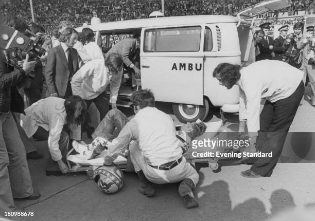 American stunt person Evel Knievel is put on a stretcher after crashing during his attempt to jump thirteen buses inside Wembley Stadium, London,...