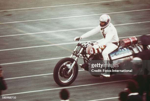 American stunt person Evel Knievel rides a three wheeled motorcycle on an athletics track, circa 1977.