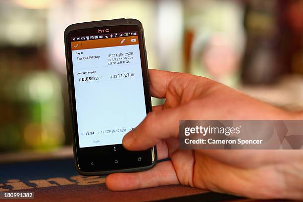 In this photo illustration, a customer pays for drinks at the Old Fitzroy Pub using bitcoins on September 19, 2013 in Sydney, Australia. The Old...