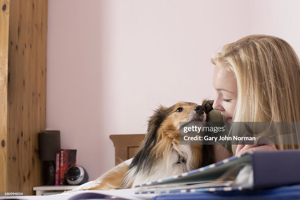 Happy teenage girl and dog in bedroom
