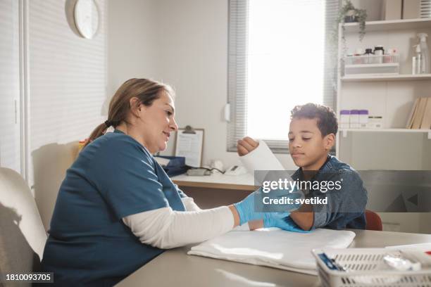 kind mit armverletzung in der arztpraxis - knochenbruch stock-fotos und bilder