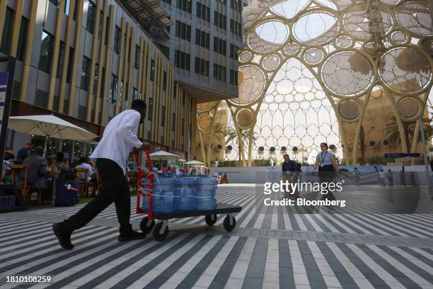 Worker transports a trolley of water containers through the Blue Zone past Al Wasl dome ahead of the COP28 climate conference at Expo City in Dubai,...