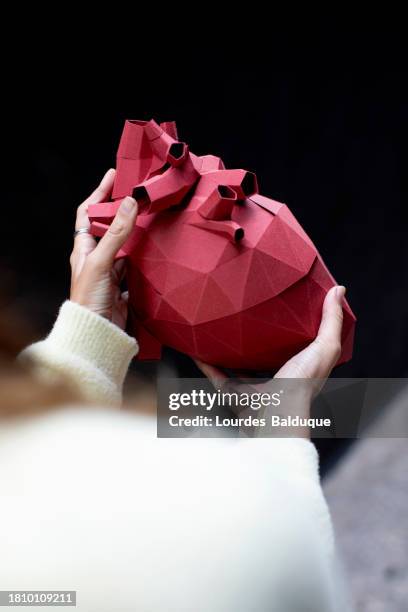 woman holds origami heart with her hands, origami, paper crafts - organspende stock-fotos und bilder